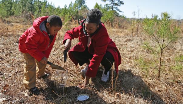 Mother and child collect soil from site of a lynching in Alabama