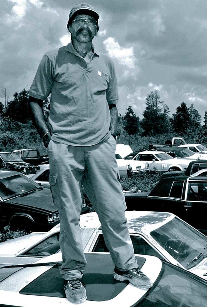 Walter McMillian standing on a car in his junkyard after his release from death row.